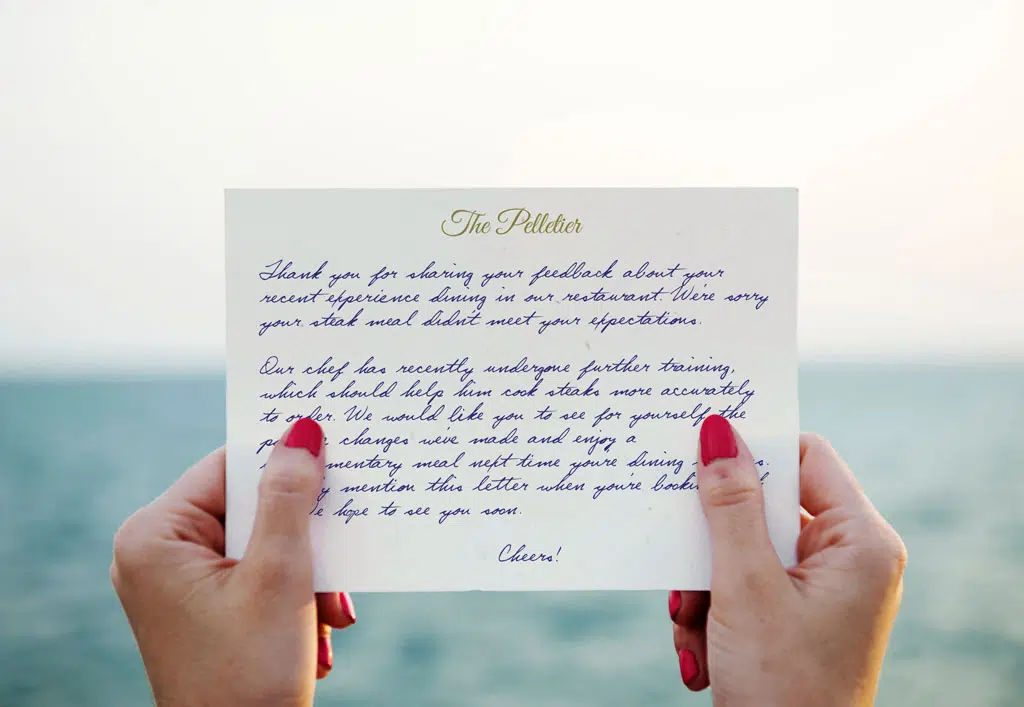 handwritten card being held by a woman on a beach