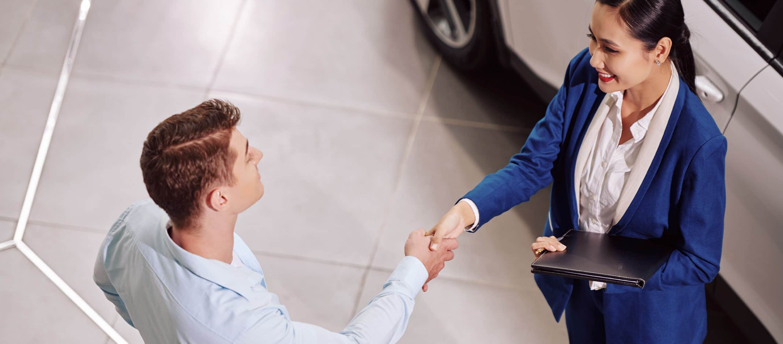 sales rep at car dealership shaking hands with customer